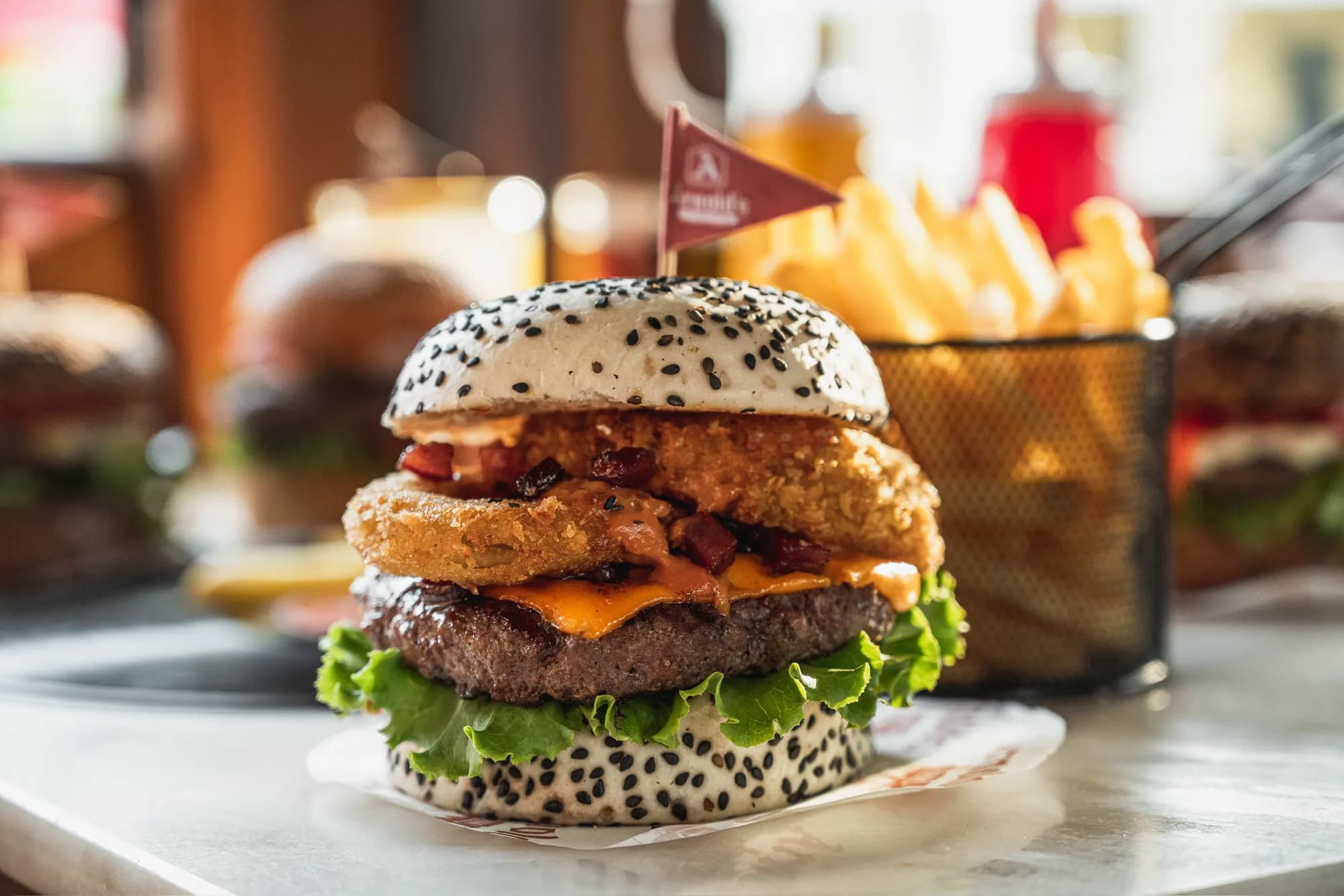 Hamburguesa de Arnold's con aros de cebolla, tocino y su banderín, con papas al fondo